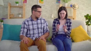 oturma odasında oturan genç hayal kırıklığına uğramış evli çift negatif gebelik testi hakkında bilgi ediniciler