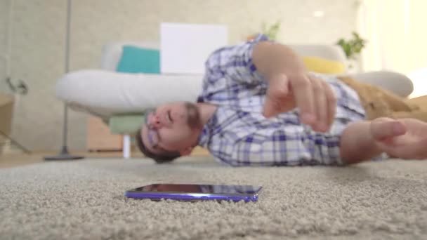 Den unge mannen hade ett epileptiskt beslag och han försöker nå smartphone liggande på golvet — Stockvideo