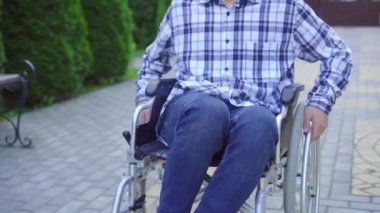 Portre genç Asyalı adam parkta tekerlekli sandalye sürmek engelli