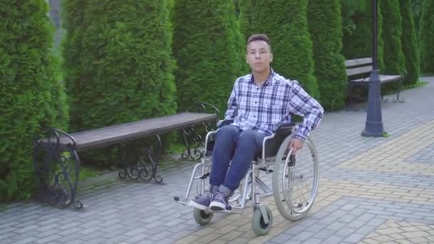 Молодой азиат катается на инвалидных колясках в парке — стоковое видео