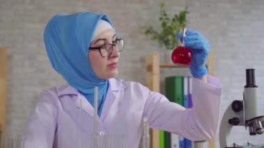 genç müslüman kadın bilimsel kimyager laboratuvar asistanı ulusal eşarp laboratuvarda çalışan slow mo