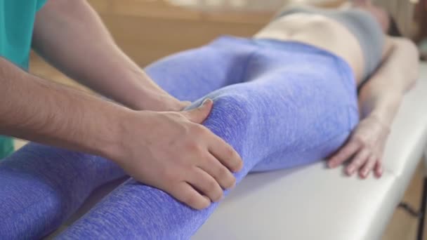 Quiroprático terapeuta trata os atletas de joelho feridos paciente do sexo feminino de perto — Vídeo de Stock