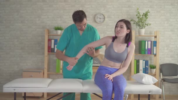 Osteópata quiropráctico examina la mano enferma de una joven atleta — Vídeo de stock