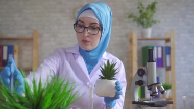 bitki üzerinde deneyler yürüten laboratuvarda çalışan ulusal bir eşarp müslüman kadın bilimsel botanikçi