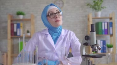 Düşünceli genç müslüman kadın bilim adamı kimyager ulusal eşarp laboratuarda çalışıyor