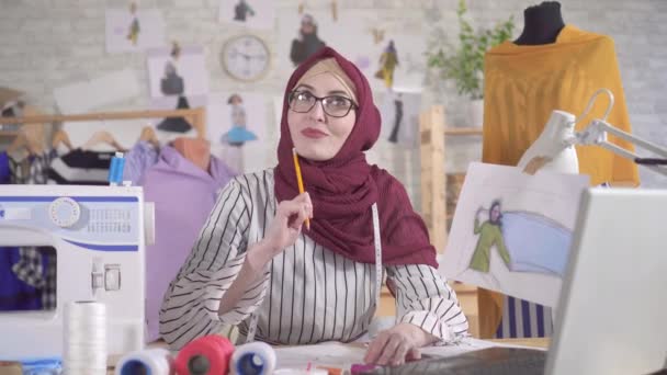 Jonge moslim vrouw mode-ontwerper in nationale hoofddoek tekent een schets — Stockvideo