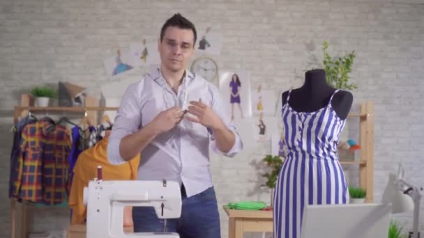 Retrato de um jovem designer de moda masculino em um estúdio moderno ao lado de um manequim — Vídeo de Stock