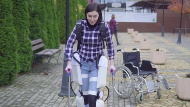 Hermosa joven paralizada mujer discapacitada está aprendiendo a caminar de nuevo con la ayuda de un exoesqueleto — Vídeos de Stock