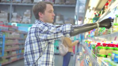 Süpermarkette biyonik protez kolu olan genç bir adam.