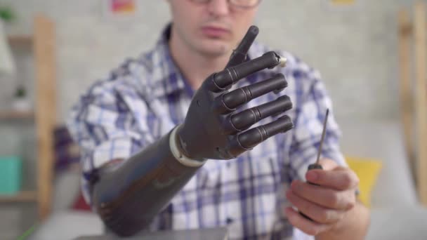 Young man adjusts a bionic prosthetic hand with a screwdriver close up — Stock Video