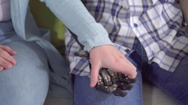 Młoda kobieta trzyma bioniczną dłoń swojego młodego mężczyzny z bliska — Wideo stockowe