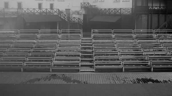 Bancs vides sur tribune avec scène fond noir et blanc — Photo