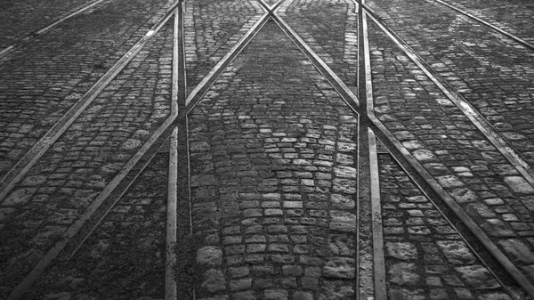 Traversée des rails de tramway sur chaussée de pierre dans la ville fond noir et blanc — Photo