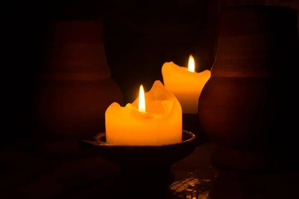 어둠 속에서 두 개의 불타는 촛불. 테이블에 클레이 머그잔. 빛나는 불꽃 — 스톡 사진
