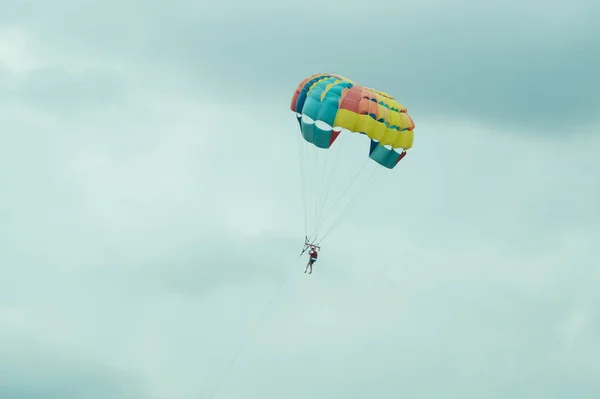 Paracaidista volando con un colorido paracaídas en el fondo del cielo —  Fotos de Stock