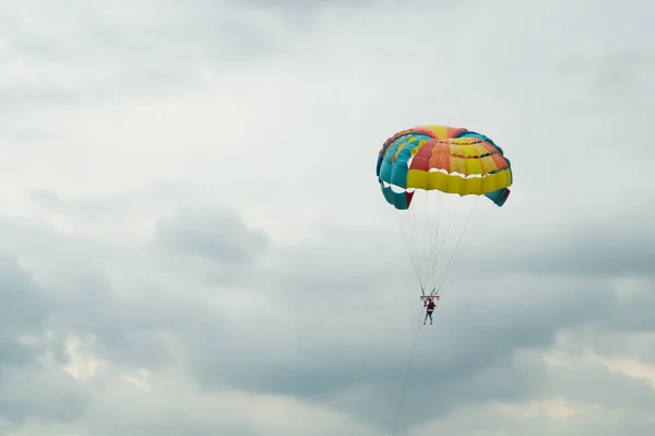Skydiver voando com um paraquedas colorido no fundo do céu — Fotografia de Stock