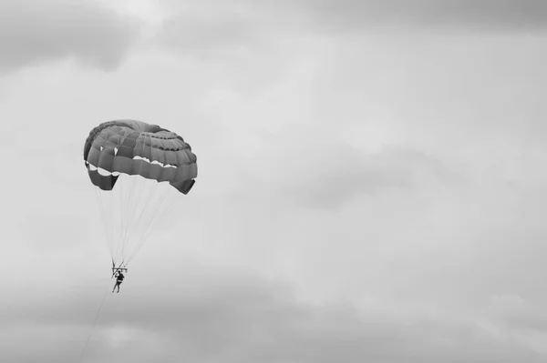 Fallschirmspringer fliegen mit einem Fallschirm schwarz-weiß Hintergrund — Stockfoto