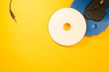 Sarı arka planda ses jakı bulunan CD çalar ve kompakt disk