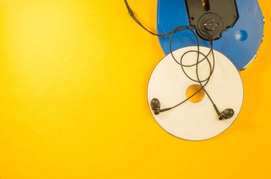 Sarı arka planda kulaklık içeren CD çalar ve kompakt disk