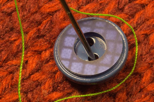 Botão e agulha com fio sobre fundo têxtil — Fotografia de Stock
