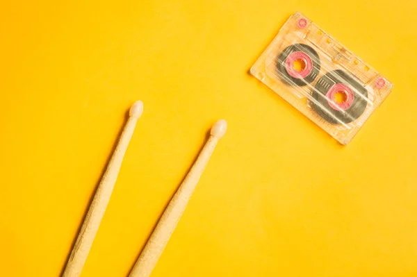 Drumsticks and cassette on yellow background — Stock Photo, Image