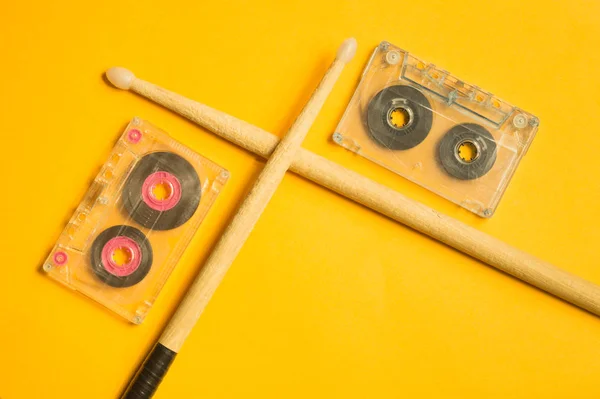 Drumsticks and cassette on yellow background — Stock Photo, Image