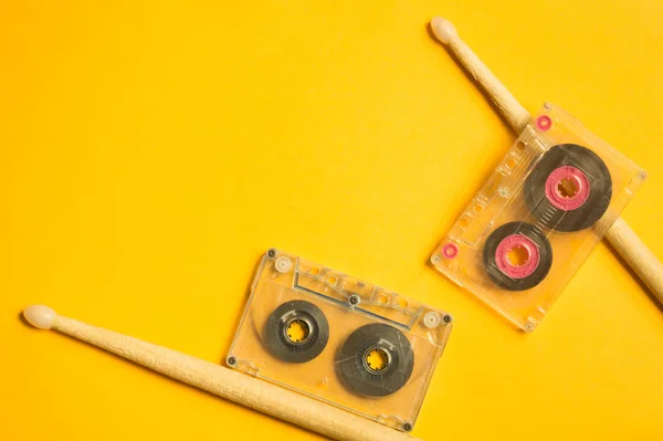 Drumsticks and cassette on yellow background — Stock Photo, Image