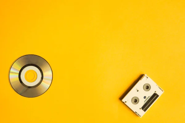 Compact disc and digital video cassette on yellow background — Stock Photo, Image