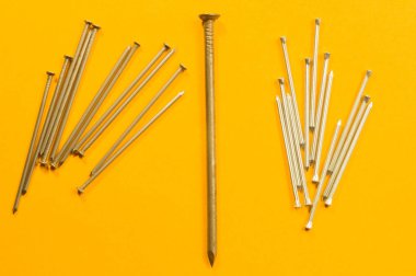 Sarı arka planda izole metal çivi. çalışma araçları