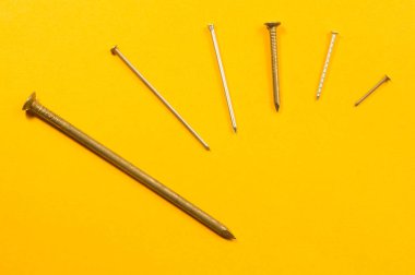 Sarı arka planda izole metal çivi. çalışma araçları