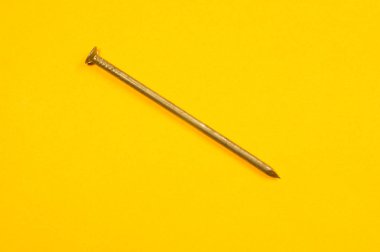 Sarı arka planda izole metal çivi. çalışma araçları