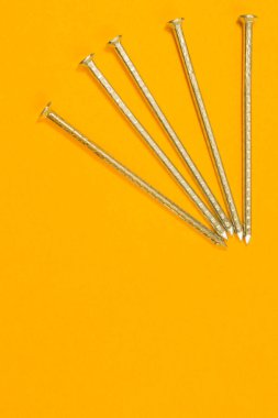 Sarı arka planda izole metal çivi. çalışma araçları