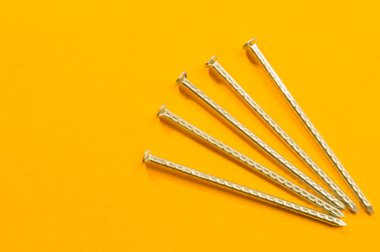 Sarı arka planda izole metal çivi. çalışma araçları