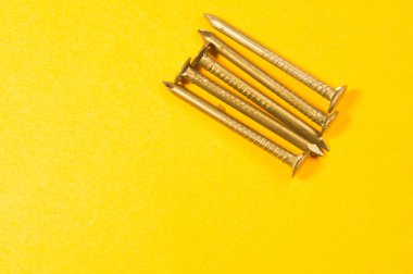 Sarı arka planda izole metal çivi. çalışma araçları