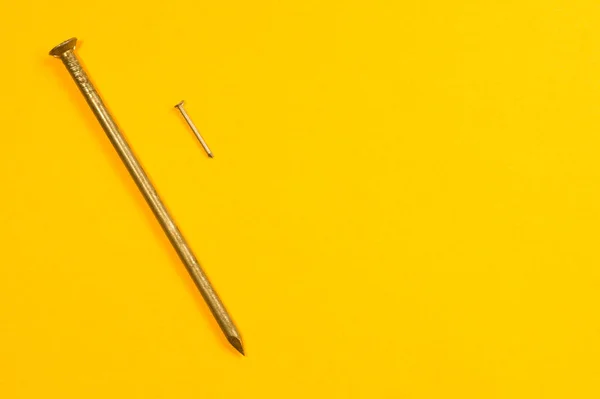 Металеві цвяхи ізольовані на жовтому тлі. робочі інструменти — стокове фото