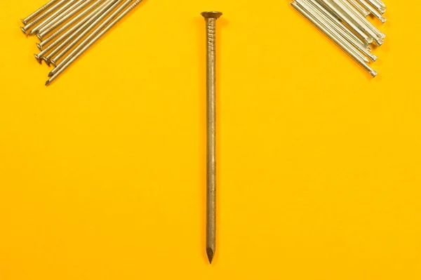 A sárga háttérrel izolált fémszögek. munkaeszközök — Stock Fotó