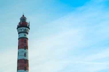 Orman arazisinde yüksek deniz feneri. kırmızı ve beyaz deniz feneri