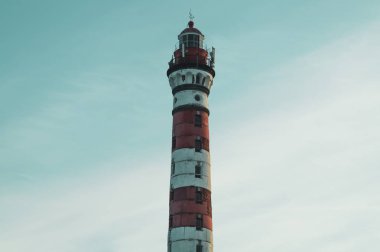 Orman arazisinde yüksek deniz feneri. kırmızı ve beyaz deniz feneri