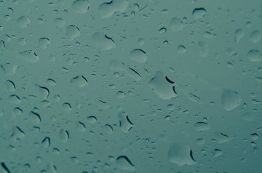 Pencerede yağmur damlaları var. Cam makronun üzerine yağmur damlaları. Su damlaları pencereye düşüyor. Yağmurlu gün