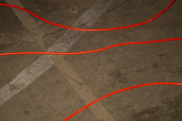 Cable eléctrico rojo. alambre rojo yace en el suelo. desorden en piso de cemento — Foto de Stock