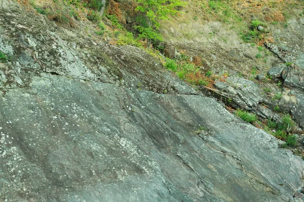Roche de pierre stratifiée recouverte d'herbe et de mousse. texture des roches de pierre — Photo