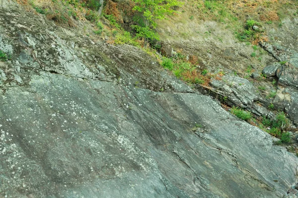 Rocha de pedra em camadas coberto com grama e musgo. textura de pedras rochas — Fotografia de Stock