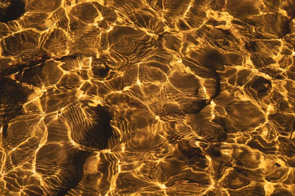 Shiny transparent water. clear water with pebbles and stone on the bottom. shining reflections of sun rays and ripples on the water — Stock Photo, Image