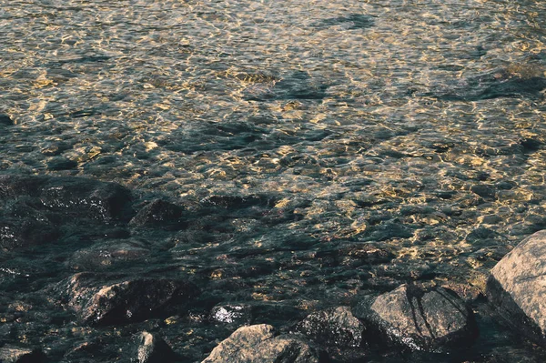 Agua transparente brillante. agua clara con guijarros y piedra en la parte inferior. reflejos brillantes de rayos de sol y ondas en el agua — Foto de Stock