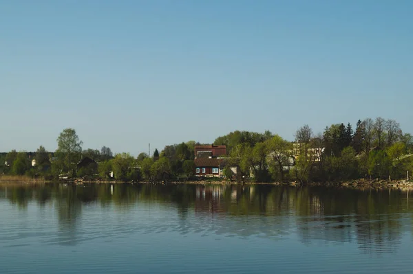 Dom nad jeziorem. Dom na brzegu we wsi. krajobraz z refleksją nad wodą — Zdjęcie stockowe