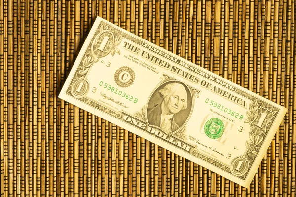Un dólar sobre un fondo de bambú de madera. dinero sobre la mesa — Foto de Stock