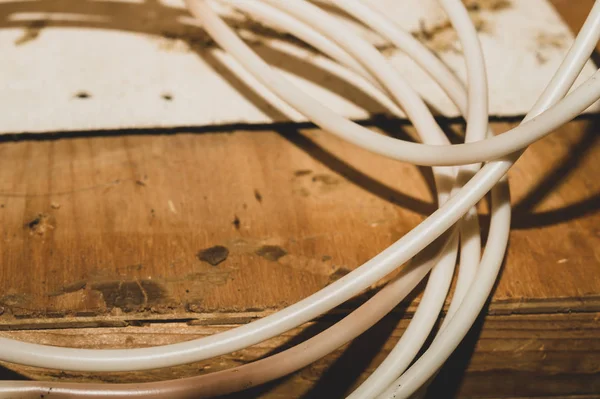 Beyaz kablo ahşap masanın üzerinde yatıyor. bağlantı teli — Stok fotoğraf