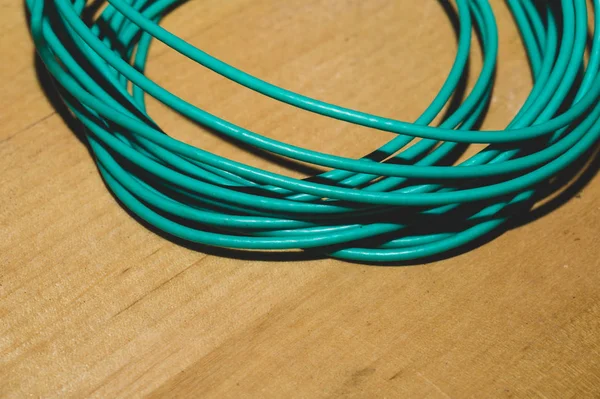 Cable verde sobre fondo de madera. alambre de conexión se encuentra en la mesa de madera — Foto de Stock