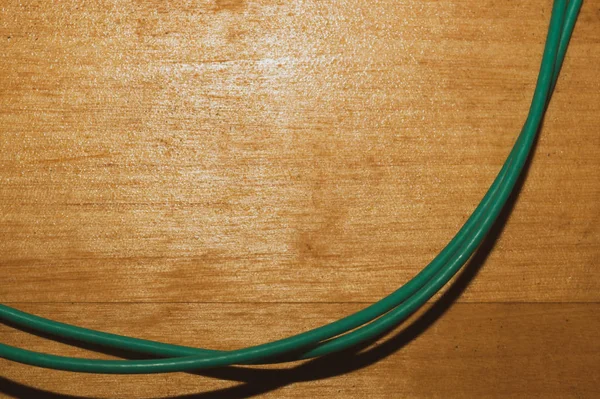 Cable verde sobre fondo de madera. alambre de conexión se encuentra en la mesa de madera — Foto de Stock