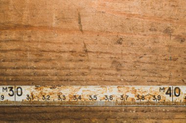 Çalışan ahşap bir masa üzerinde siyah numaraları ile eski paslı cetvel. vintage ölçüm bandı. endüstriyel arka plan